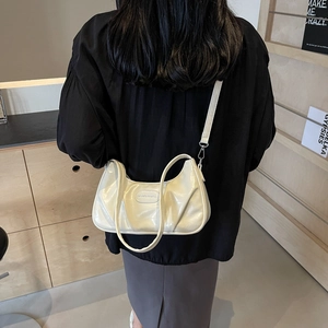 Sac croissant plissé blanc crème chic avec finition brillante porté à l'épaule