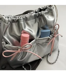 Detail showing silver metallic crossbody bag with dual front pockets and pink bow accents
