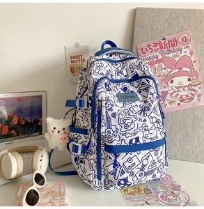 Nahaufnahme vom Graffiti-Schulrucksack mit Bären-Anhänger und Laptop-Lernumgebung