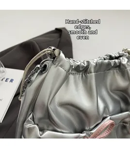 Detailed view of hand-stitched silver leather bag with a pink bow and metal chain