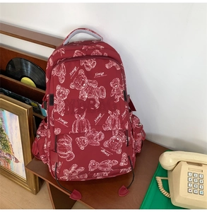 Retro-Aufnahme von weinrotem Schulrucksack mit Bärenmuster und Staufächern