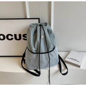 Detail view of the drawstring closure and mesh splicing on the nylon canvas backpack