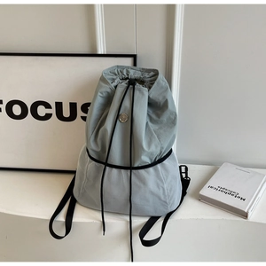 Detail of light blue nylon and grey mesh backpack with drawstring and metal logo buckle