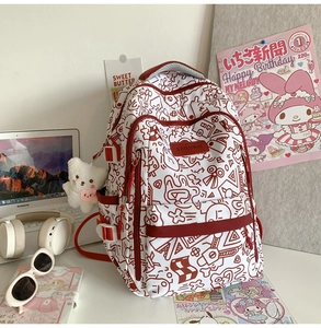 Detail eines weiß-roten Graffiti-Rucksacks mit süßem Plüschbär-Anhänger und Seitenfächern