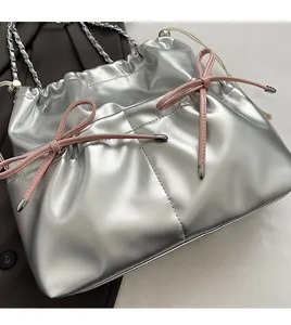 Detail of silver metallic drawstring bag with pink bows and elegant chain strap