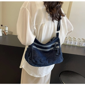 Deep blue denim crossbody bag featuring three-tier zipper pockets and pleated side detail