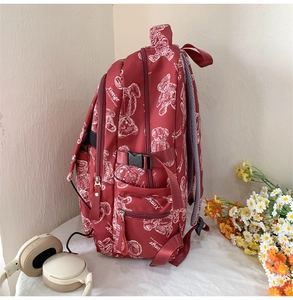 Detail eines weinroten Schulrucksacks mit Bärenprint und seitlichen Schnallenriemen