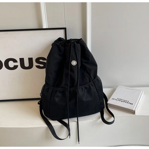Detail of black nylon backpack featuring drawstring closure and side mesh pockets