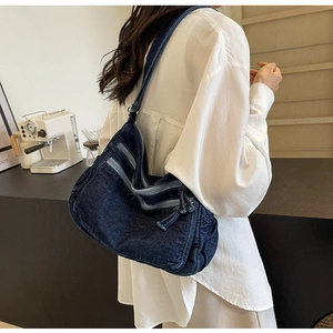 Detail view of large capacity blue denim crossbody bag with multiple zipper pockets