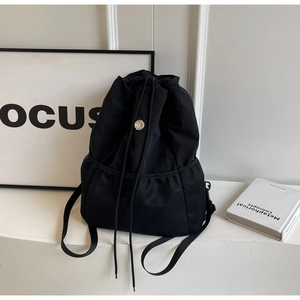 Detail of black nylon drawstring backpack with metal emblem and mesh pocket