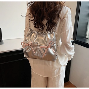 Detail of a silver metallic drawstring bag featuring pink bows and a sleek chain strap