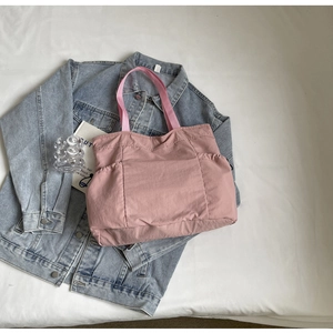 Detailweergave van roze nylon draagtas met zijzakken op een denim jasje achtergrond