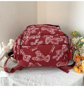 Detailansicht dunkelroter Rucksack mit weißen Bärenprints und vorderer Reißverschlusstasche