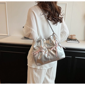 Silver PU leather shoulder bag with pink bows and chain strap worn by a model
