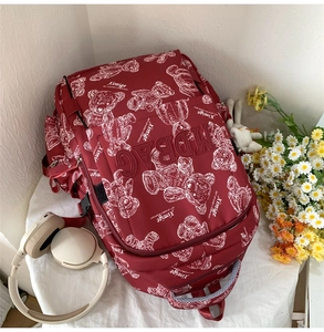 Details des burgunderroten Studentenrucksacks mit Bärenskizzen und geprägtem MODBAG-Logo