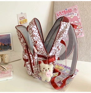 Detail eines Schulrucksacks mit rotem Graffiti-Design und Plüschbär-Schlüsselanhänger