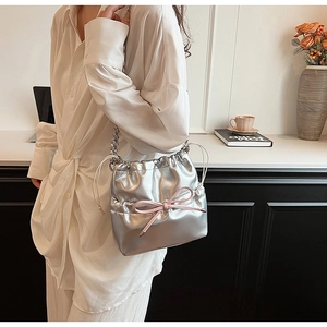 Silver metallic drawstring bucket bag with pink bow accent and chain strap detail