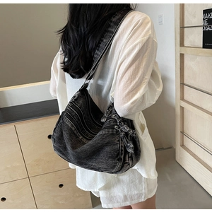 Detail of hobo crossbody bag in washed denim with multi-zipper layers and fringe