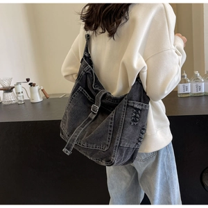 Detail der schwarzen verwaschenen Denim-Einkaufstasche mit Metallschnalle und Fransen