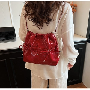 Detail of red glossy backpack featuring ribbon bows and silver chain straps