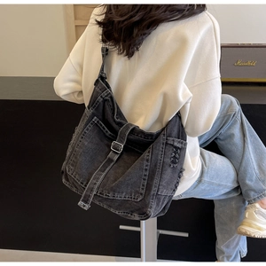 Detail view of washed denim crossbody bag featuring frayed holes and adjustable strap
