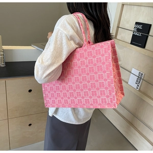 Roze canvas bruidstas met rode Xi-tekens getoond in een realistische setting