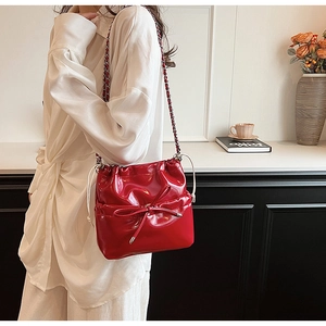 Close-up of red patent leather bucket bag with bow detail and silver chain strap