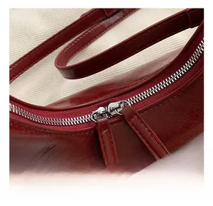 Close-up of premium wine red leather handbag featuring smooth dual silver zippers