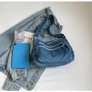 Flat lay of vintage denim crossbody bag with multiple zippers and matching accessories