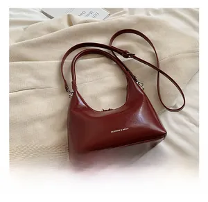Detail of burgundy glossy leather bag with Fashion & Bags text on neutral backdrop