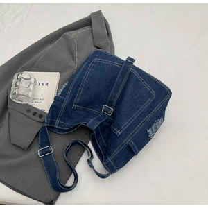 Detailed macro view of vintage blue denim bag with white stitching and distressed edge
