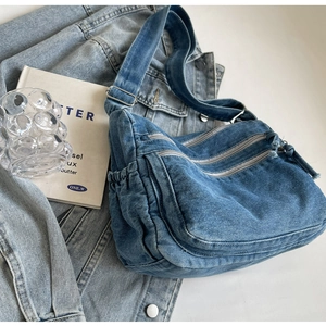 Detail of vintage blue denim crossbody bag with dual zipper and washed texture