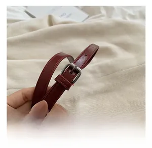 Detail of adjustable wine red leather shoulder strap with silver buckle and stitching