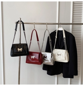 Detail of crocodile texture bags with silver butterfly buckles and chain straps