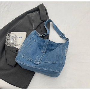Detailed macro view of distressed blue denim texture and frayed edge on a vintage crossbody bag