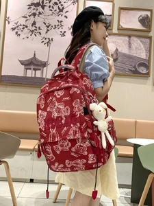 Roter Schulrucksack mit Bärenprint und Hasenanhänger am Model in einem Café gezeigt