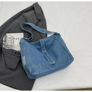 Detail of distressed denim crossbody bag with retro buckles and side pockets