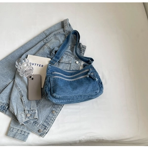 Close-up of blue denim crossbody bag with multiple zip pockets and adjustable strap