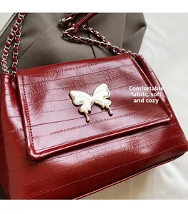 Detail of burgundy chain bag featuring metal butterfly buckle and soft leather fabric