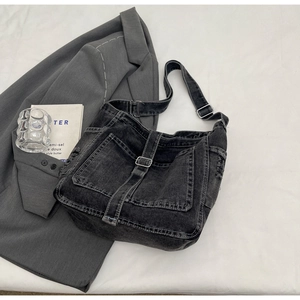 Detail of vintage washed denim shoulder bag with silver hardware and adjustable strap