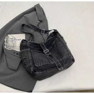 Macro shot of washed denim messenger bag featuring utility pockets and metallic buckles
