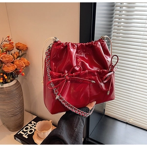 Detail of red patent leather drawstring bucket bag with silver chain and bow detail