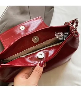 Detail of the magnetic snap closure on a dark red quilted leather chain bag