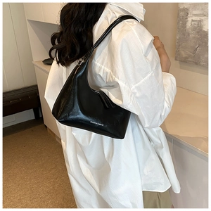Side view of black hobo bag with white text print on shoulder for size reference
