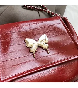 Detail of red vintage leather bag with liquid gold butterfly buckle and chain strap