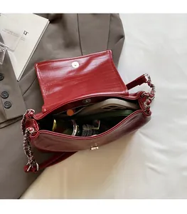 Deep red glossy leather bag interior showing spacious capacity and silver chain strap