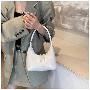 Detail of white patent leather shoulder bag with smooth curves and a metallic zipper