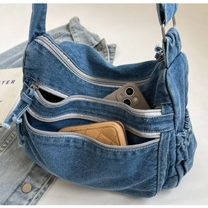 Detailed macro view of denim crossbody bag showing multi-zipper pockets and washed texture