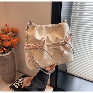 Detail of cream pleated bucket bag with pink bows and silver chain strap details