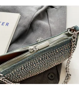 Detail view of denim handbag featuring silver dome studs and a chunky metal chain strap